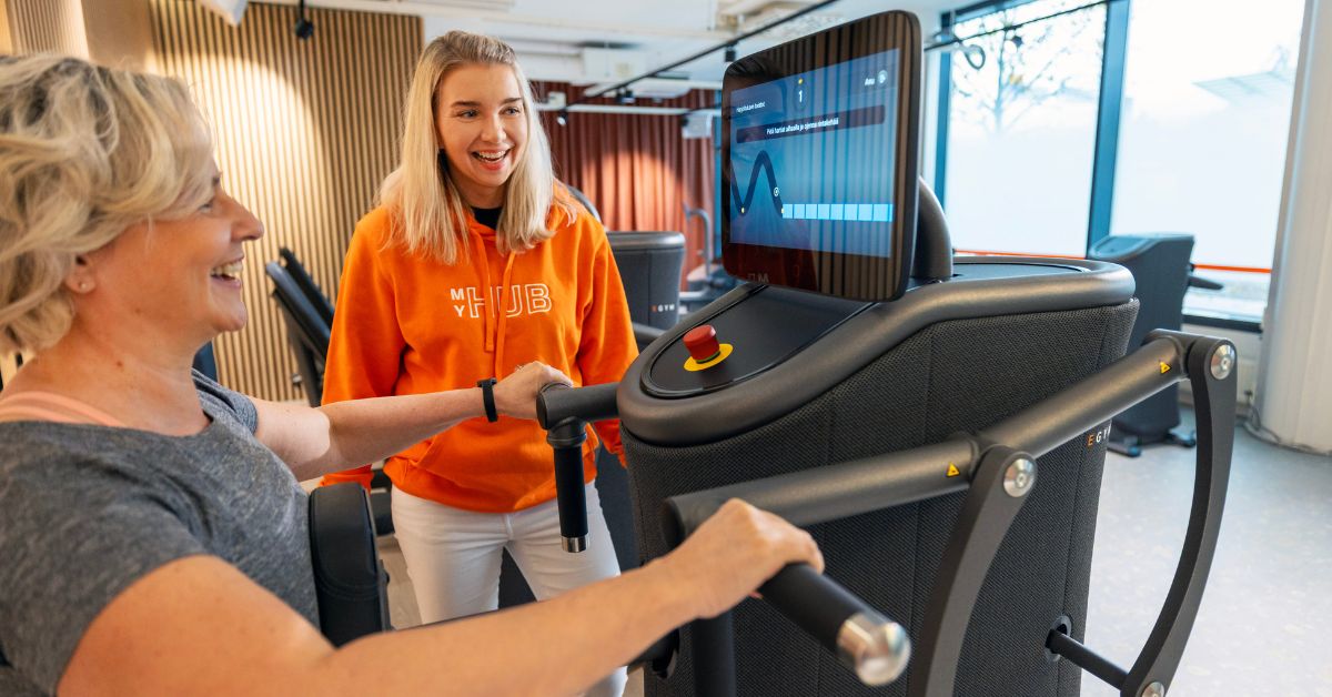 Nainen tekee MyHubilla egym-treeniä, MyHubin hosti seuraa vieressä.