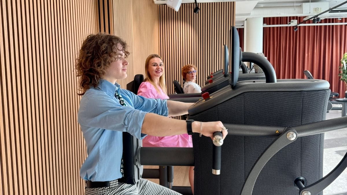 MyHubin asiakkaat tekemässä treeniä EGYM-laitteilla. Naisilla mekot päällä ja miehellä kauluspaita, solmio ja suorat housut.