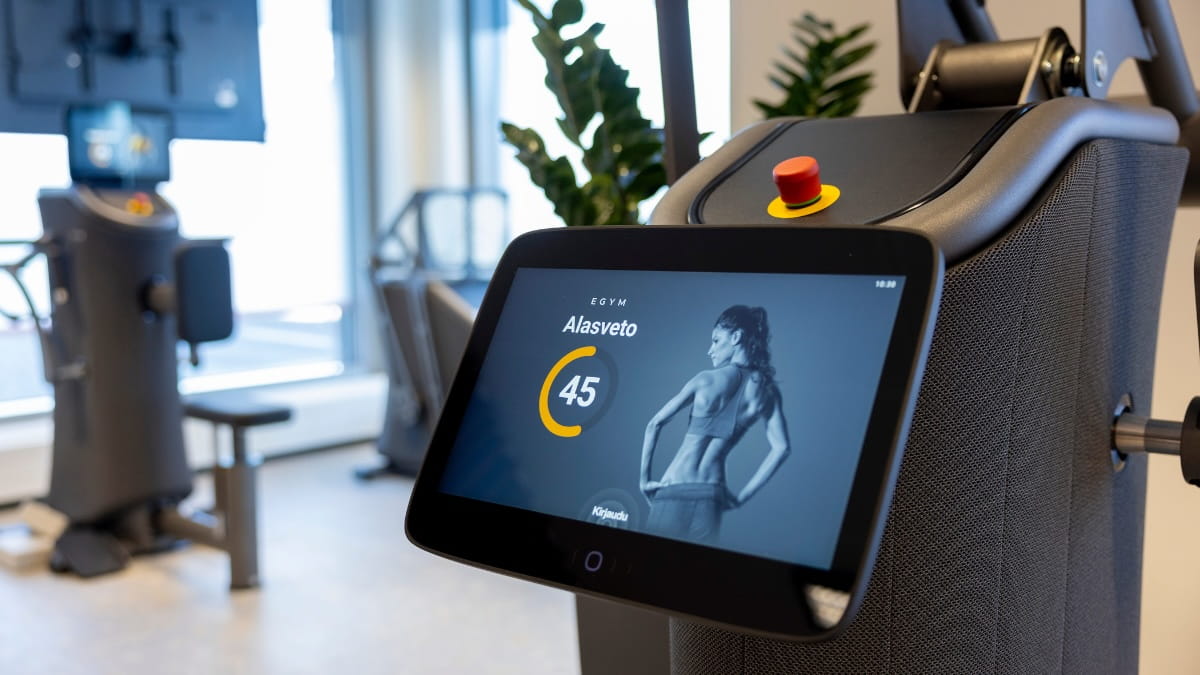 EGYM-alasvetolaite MyHubin salilla, näytöllä voimaharjoitteluliikkeen ohjauskuva ja kuluva aika
