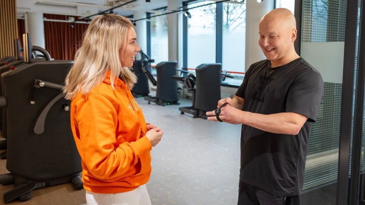 Mies on tulossa MyHubille ja saa hostilta rannekkeen, jolla pääsee EGYM-laitteisiin.