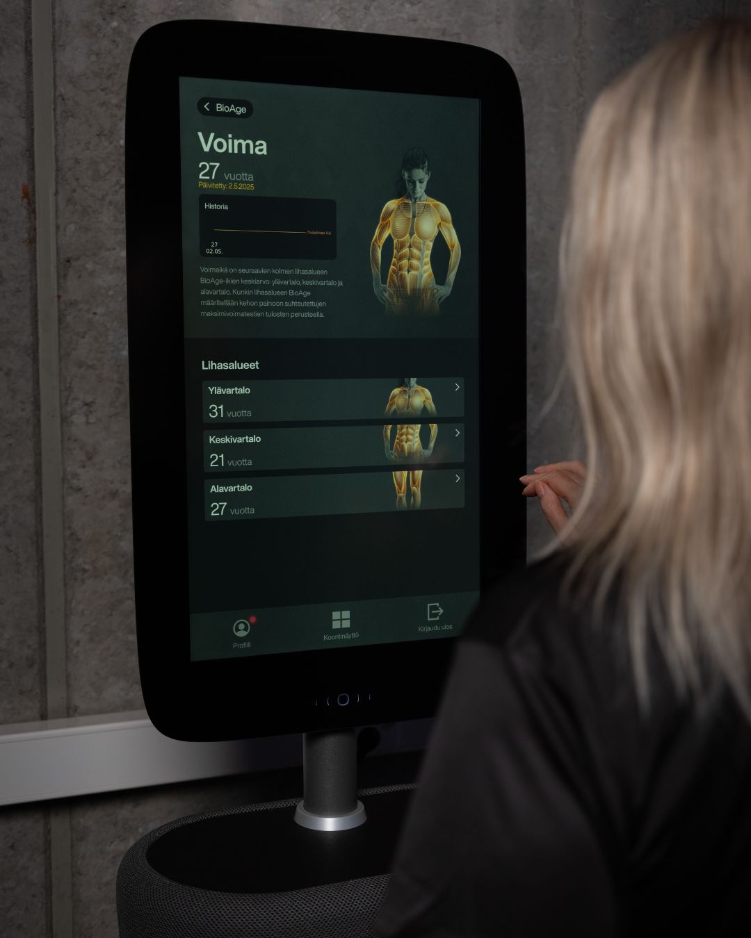 Kuvassa nainen katsoo omaa voima kehitystä EGYM-laitteelta